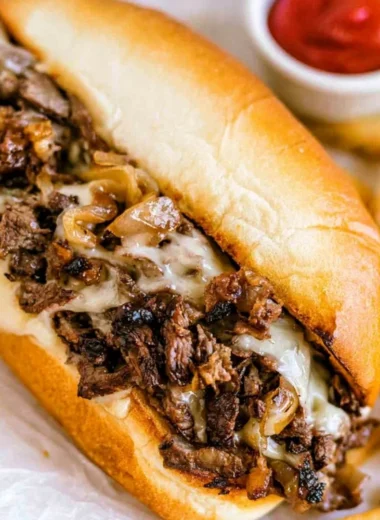 Delicious homemade Philly Cheesesteak served with toppings and a side of fries