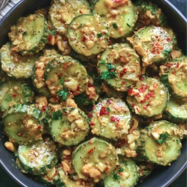 Delicious cucumber salad topped with creamy peanut sauce and garnished with herbs.