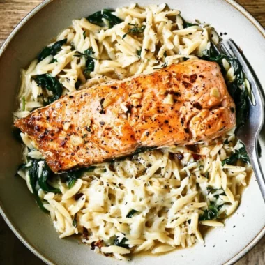 One Skillet Salmon with Lemon Orzo dish garnished with lemon slices.