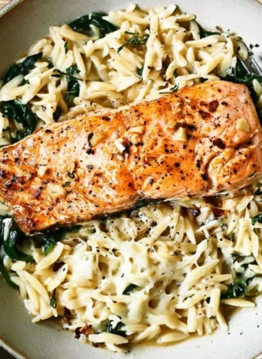 One Skillet Salmon with Lemon Orzo dish garnished with lemon slices.