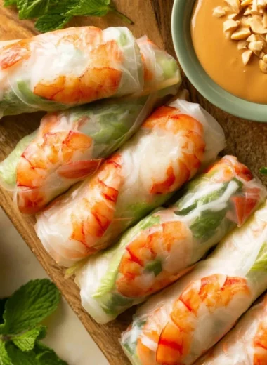 Plate of traditional Vietnamese fresh spring rolls filled with colorful vegetables and shrimp.